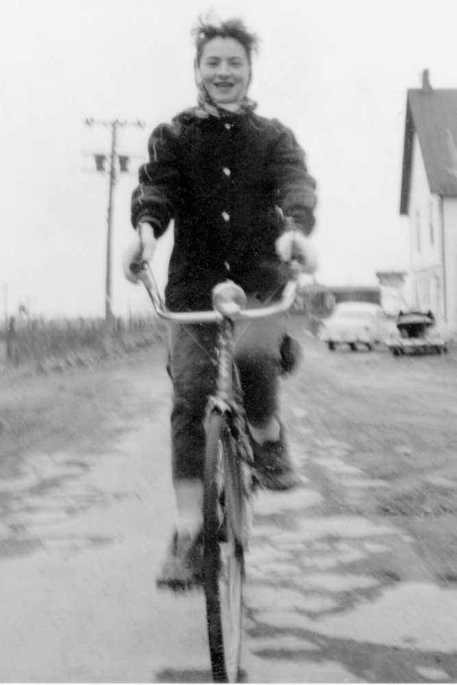 atricia ODuffy on bike in front of Laflamme Barber shop in Wales 1956
